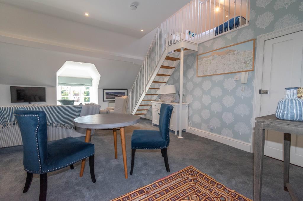Lot: 29 - CHARACTERFUL FLAT IN A DESIRABLE NORFOLK COASTAL TOWN - Living room with window to front and stairs to gallery bedroom